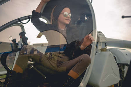 View through glass of helicopter cockpit of smiling preteen girl on pilots seatの写真素材