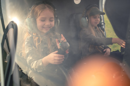 Two cheerful preteen girls in headsets at helicopter controls