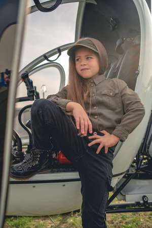 Confident preteen girl standing near open cockpit of helicopterの写真素材