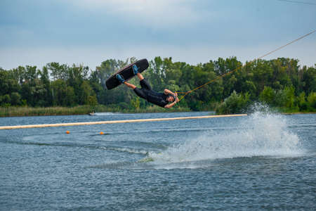 Experienced wakeboard rider jumping and spinning in air holding on to tow cableの写真素材