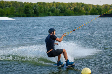 Experienced wakeboarder demonstrating freeride skills maneuvering between buoysの写真素材