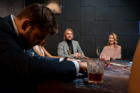 Positive people playing poker at gaming table in casino