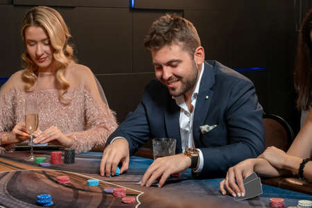 Young bearded man making bets while playing poker in casinoの写真素材