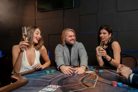 Successful man winning poker game, raking pile of gambling chips at table in casino