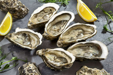Fresh raw oysters in shells halves with lemonの写真素材