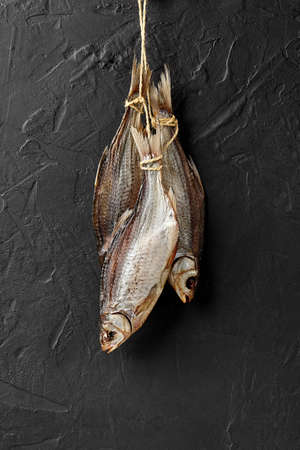 Bunch of salted dried roaches hanging on rope on black wallの写真素材