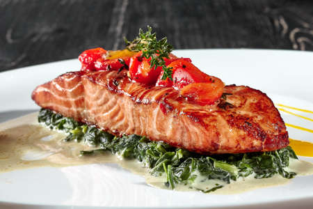 Grilled salmon steak with stewed spinach in creamの写真素材
