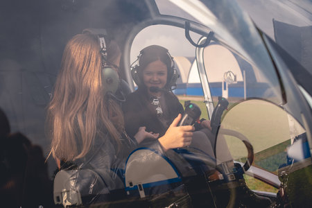 Cheerful preteen girls in headsets talking in helicopter cockpit