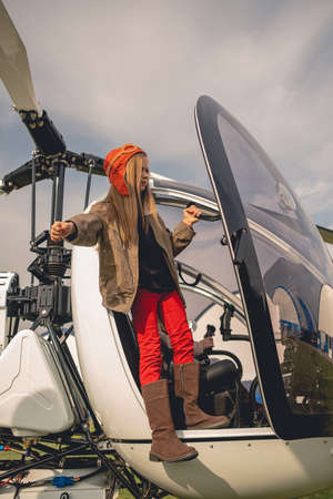 Tween girl in pilot hat looking into distance from helicopter cockpitの写真素材