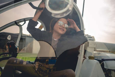 View through glass of helicopter cockpit of cheerful tween girl looking at skyの写真素材