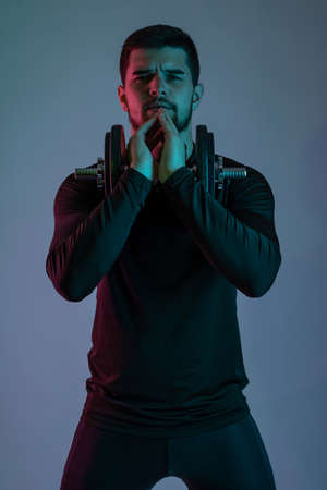 Focused young man with dumbbell on grey backgroundの写真素材