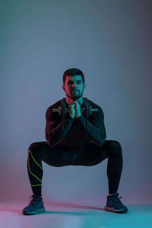 Athletic young man performing dumbbell sumo squatsの写真素材