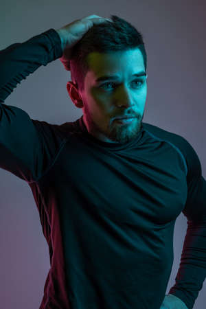 Young man in black long sleeve sports shirt touching his hair