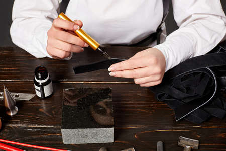 Female artisan making genuine leather handbag at table