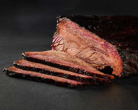 Slices of grilled veal loin in barbecue sauce on gray background