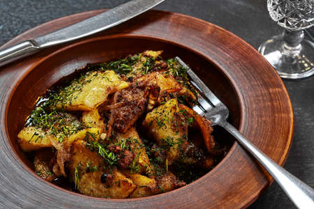Roasted potatoes with meat, onions and dill in clay plate