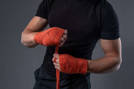 Man wrapping hands with red tape, preparing for boxingの写真素材