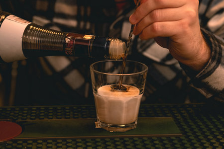Hands of male bartender preparing layered cocktail on bar counterの写真素材