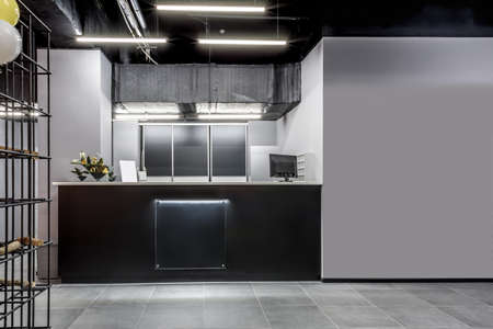 Modern interior of reception in new gym. Computer, flowers, empty blank for training schedule or...