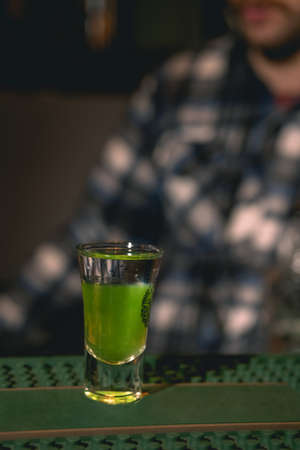 Shot glass with layered drink Green Mexican on bar counterの写真素材