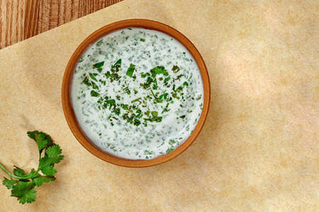 Clay bowl with creamy sauce of matsoni with fresh greensの写真素材