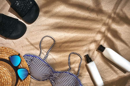 Summer background with straw hat, sunglasses, sunscreen bottle and flip flops
