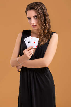 Beautiful brown-haired woman holding two aces as a sign for poker game, gambling and casino