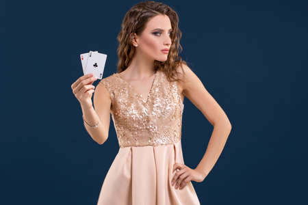 Young beautiful woman holding the winning combination of poker cards on dark blue background. Two...