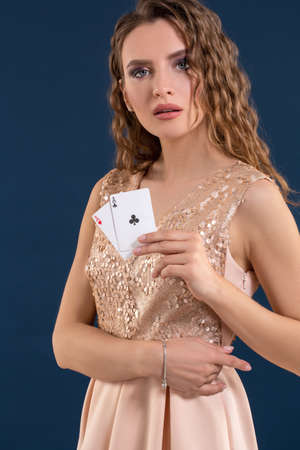 Young beautiful woman holding the winning combination of poker cards on dark blue background. Two...