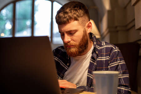 Young professional surfing the Internet on his laptop in a cafe