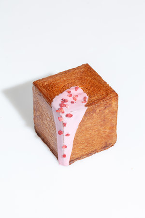Puff pastry cube shaped croissant with creamy berry sauce and candied strawberry crumbleの写真素材