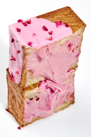 Cut in half fluffy cube shaped croissant with berry cream and candied raspberry crumble