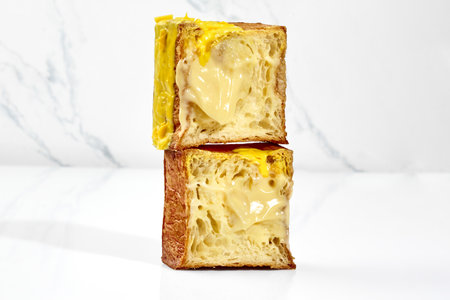 Sliced flaky cubic croissant with vanilla custard filling, yellow glaze and chocolate chips