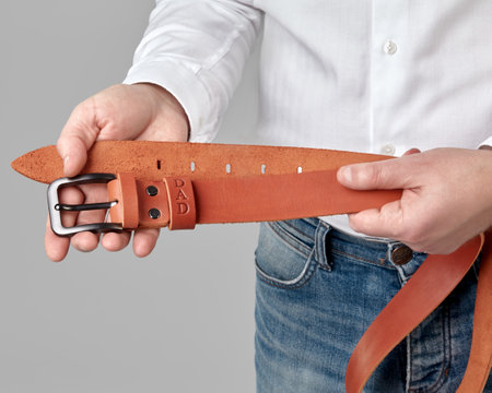 Handcrafted copper leather belt with DAD embossing in male handsの写真素材
