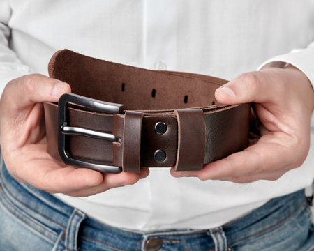 Handcrafted dark brown leather belt with DAD embossing in hands