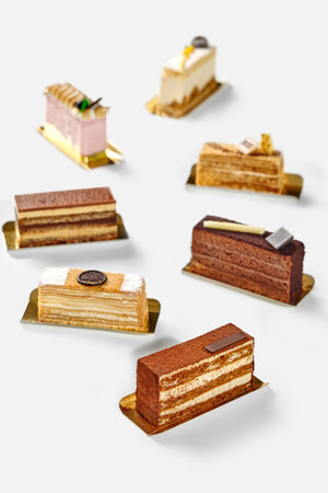 Slices of variety of exquisite cakes on white backgroundの写真素材