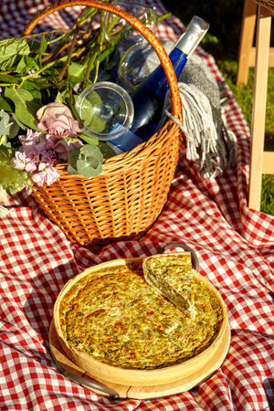 Savory quiche with bottle of wine for romantic summer picnicの写真素材
