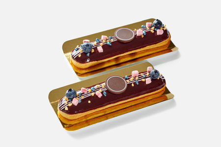 Delicious chocolate glazed eclairs with fresh blueberries and sweets