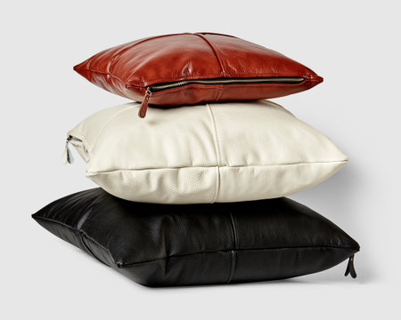 Stack of three leather pillows in brown, beige, and blackの写真素材