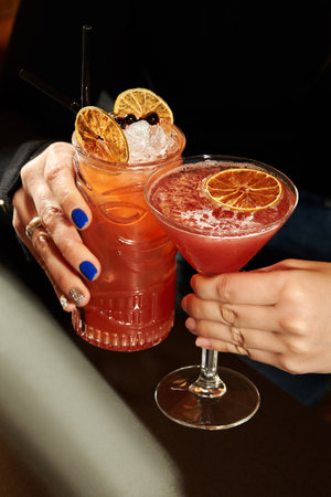 Women hands holding tropical cocktails with orange and ice cubesの写真素材