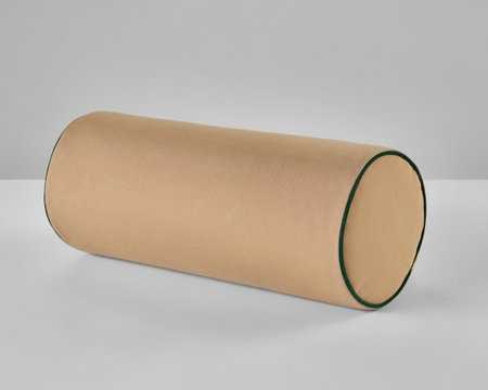 Beige bolster pillow with green border resting on white surfaceの写真素材