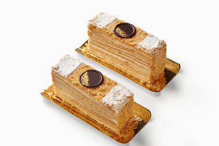 Two slices of mille-feuille cake resting on golden trays, showcasing layers of pastry and creamの写真素材