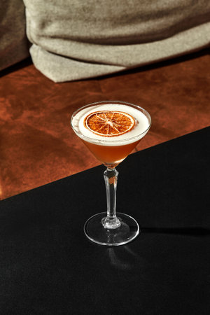 Elegant cocktail glass with dried orange slice on black table in cozy barの写真素材