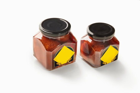 Two jars of baba al rhum showing preserved cherries in rum syrup on white backgroundの写真素材