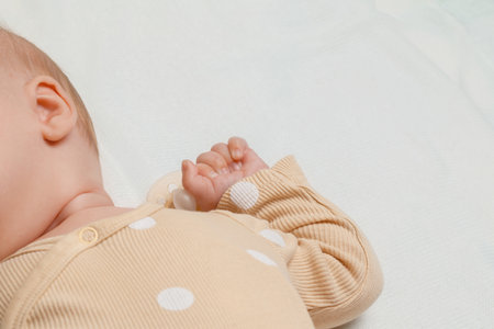 Baby sleeping peacefully with pacifier on white sheets, showing tiny handの写真素材