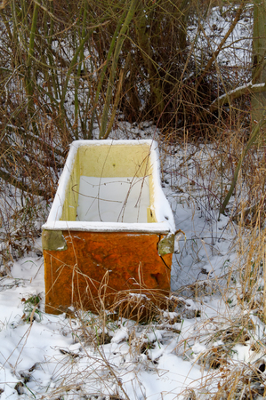 old damaged ejected snow covered fridge in the forestの写真素材