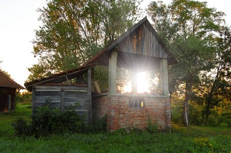 rising sun seen through old ruined shed in the countrysideの写真素材