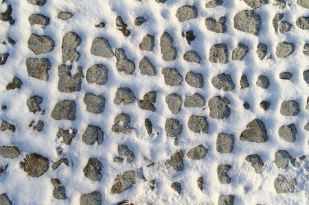 sidewalk made of cobblestone, partially covered by the snowの写真素材