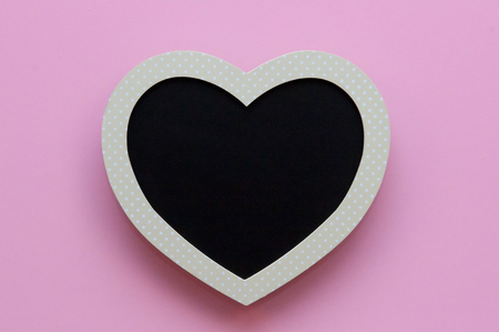 Blank heart shaped black board on a pink backgroundの写真素材