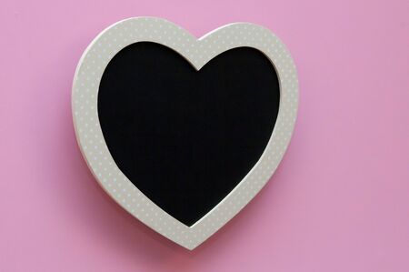 Blank heart shaped black board on a pink backgroundの写真素材